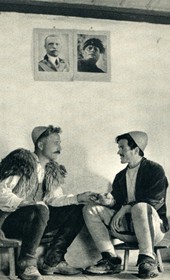 GM045: Two Shala men conversing in Theth, with photos of King Victor Emmanuel III and Mussolini on the wall (Photo: Giuseppe Massani, 1940).