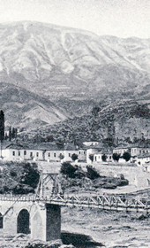FW112B: “In Albanian Epirus: the little trading town of Përmet at the foot of Mt Dhëmbel. In the front is the chain bridge over the Vjosa” (Photo: Friedrich Wallisch, 1931).